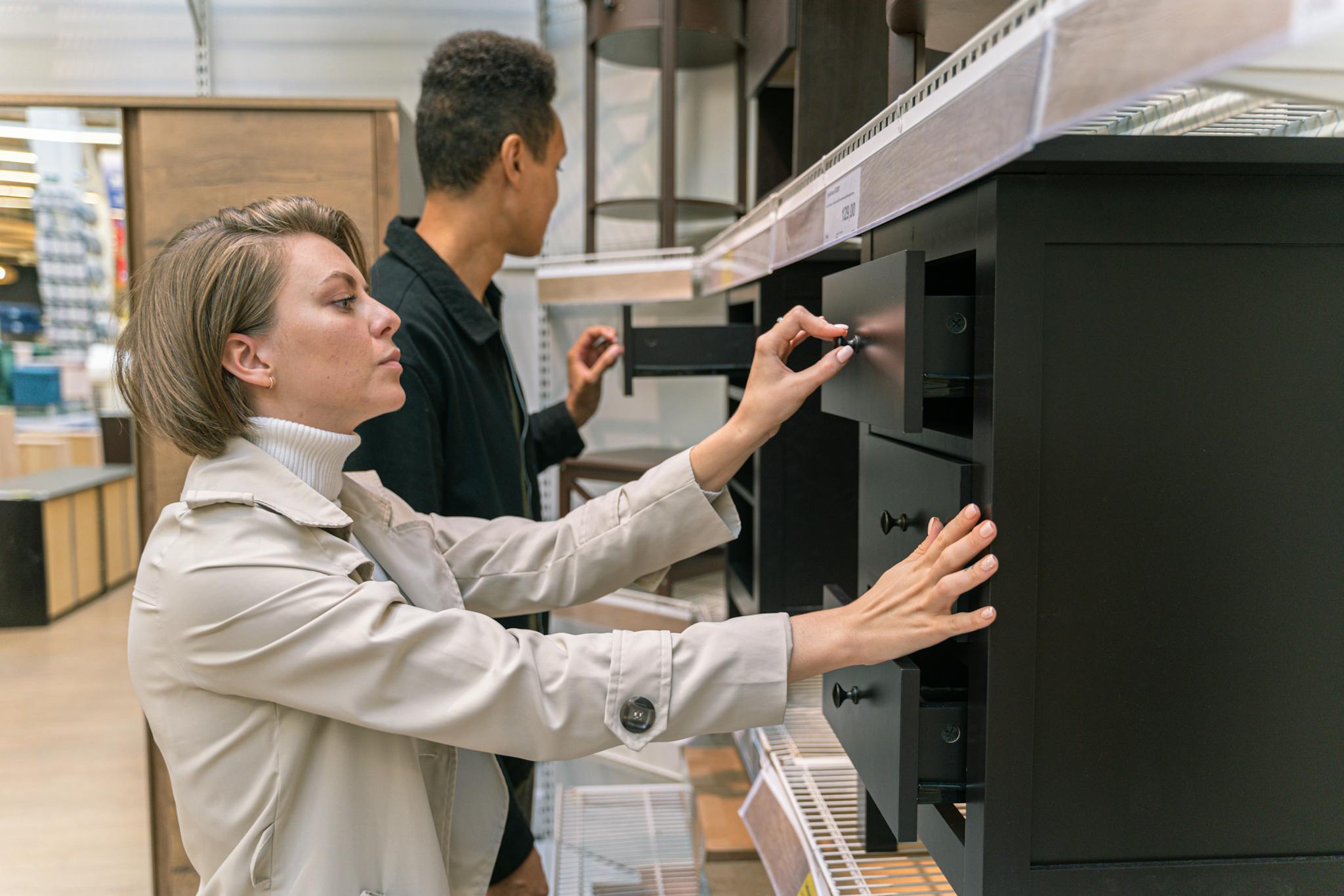 A man and woman examining drawers in a furniture store, exploring options.