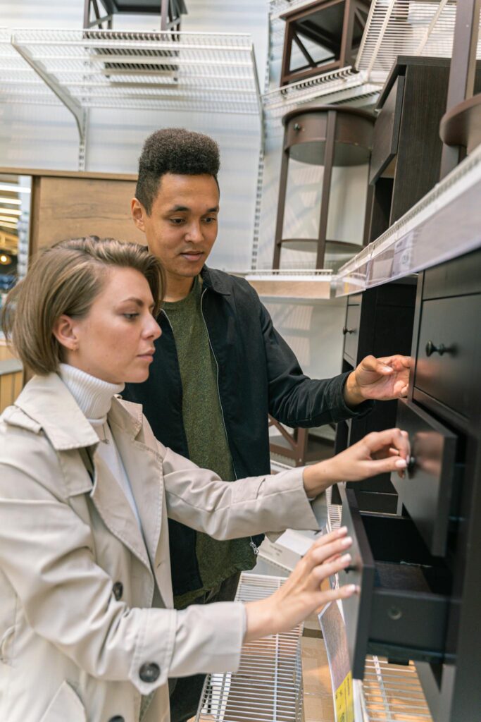 Young couple browsing furniture options in a home goods store aisle.
